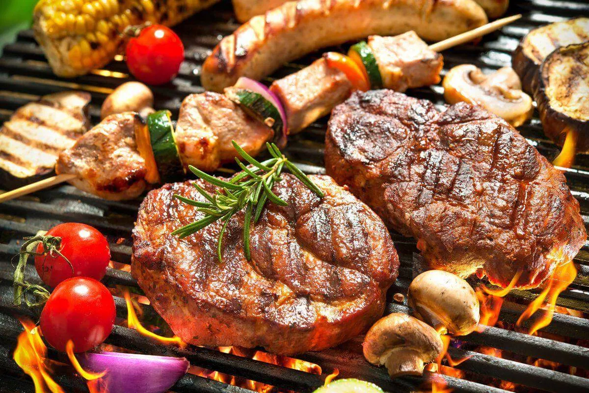 Steaks, sausage and vegetable skewers on a charcoal grill